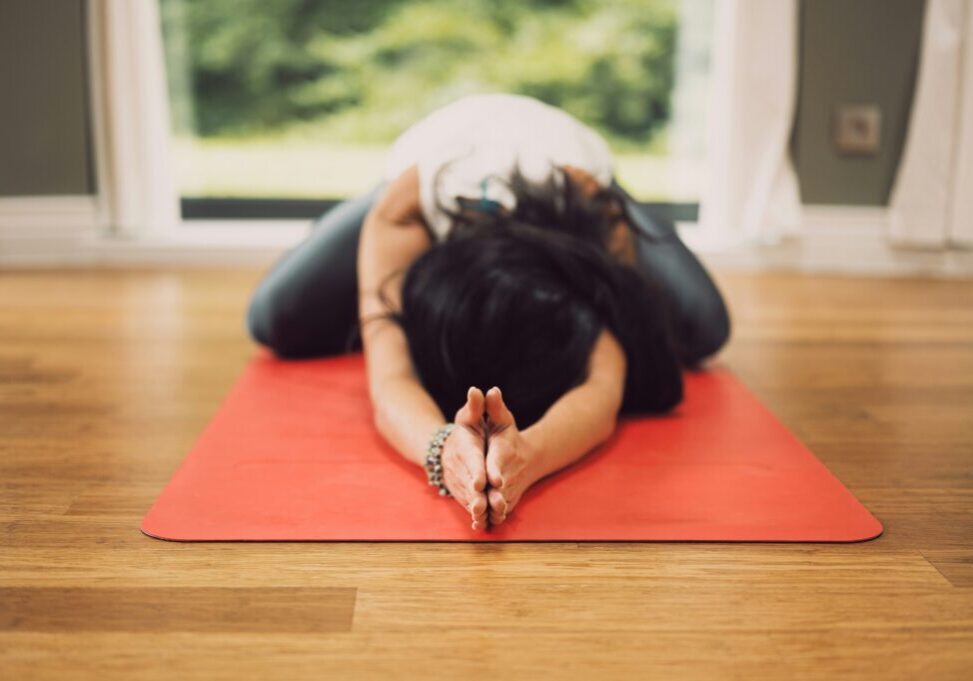 person bending over on yoga mat with arms outstretched