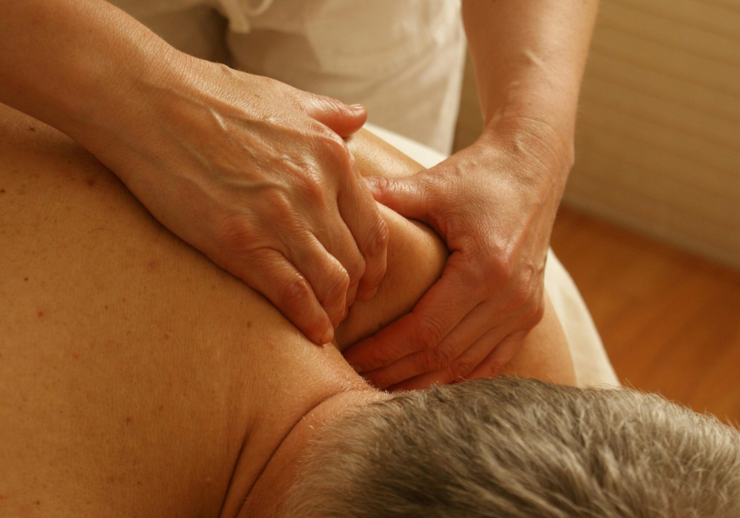 two hands massaging man's shoulder